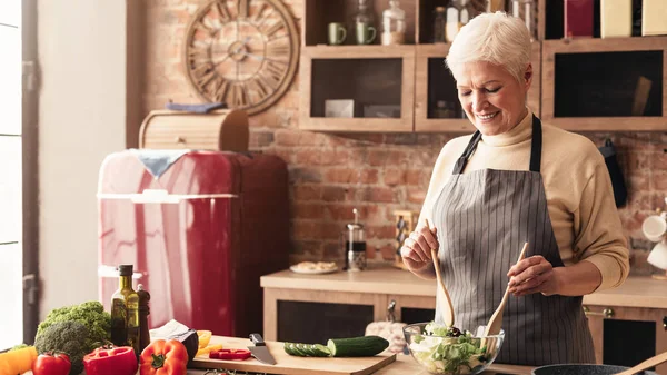 Seniorin bereitet in Küche frischen Bio-Salat zu — Stockfoto
