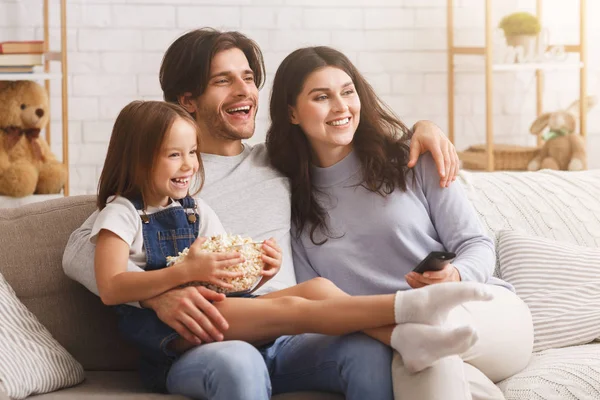 Glad familj tittar på tv tillsammans, äter popcorn och kopplar av hemma — Stockfoto