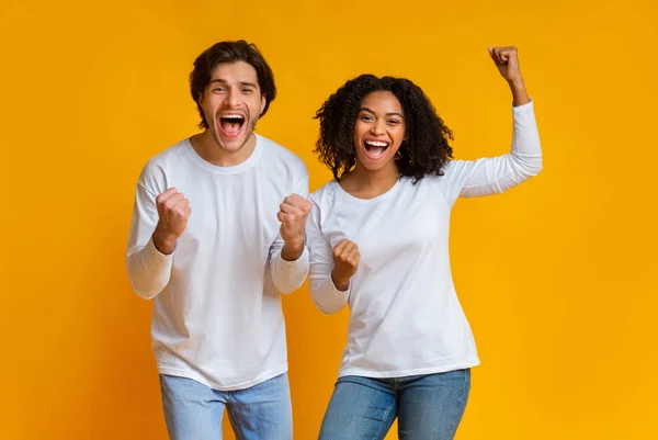 Pareja multirracial muy alegre celebrando el éxito con los puños levantados, exclamando con emoción —  Fotos de Stock