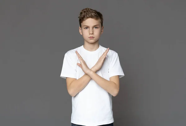 Teen boy gesturing crossed hands, grey studio background — Stock Photo, Image