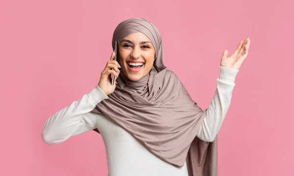 Meglepett iszlám lány Hidzsáb beszél mobilon keresztül rózsaszín háttér — Stock Fotó