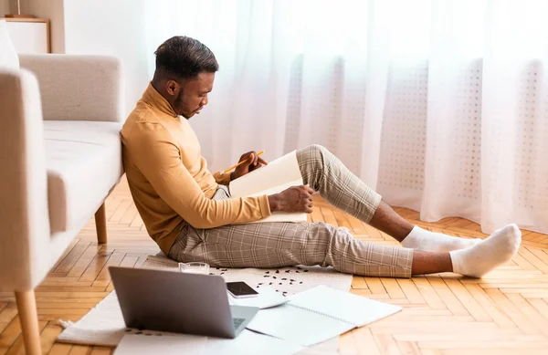 Africano preparándose para el examen sentado en el suelo en casa —  Fotos de Stock
