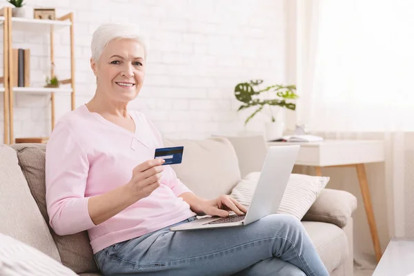 Moderne Seniorin überprüft ihr Kreditkartenguthaben auf Laptop — Stockfoto