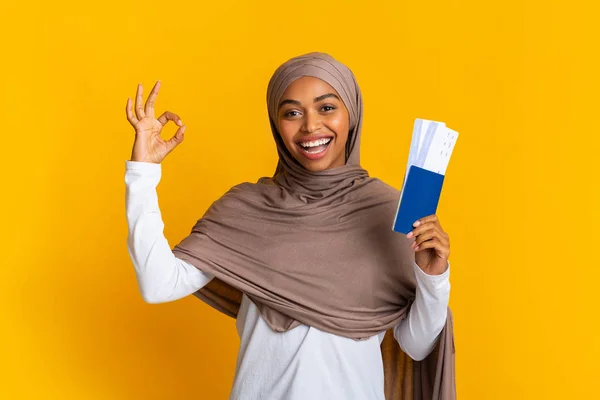 喜庆的非洲裔伊斯兰女孩，持护照和机票，为签名打手势 — 图库照片