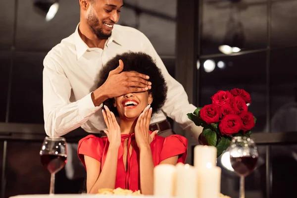 Homem que cobre os olhos das mulheres que prendem o buquê que celebra Valentine no restaurante — Fotografia de Stock