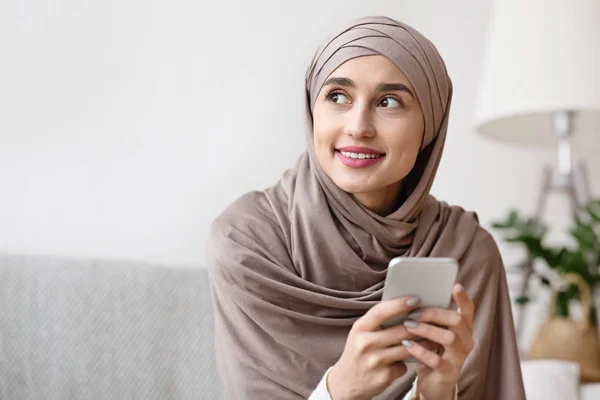 Портрет задумчивой арабской девушки в хиджабе со смартфоном в руках — стоковое фото
