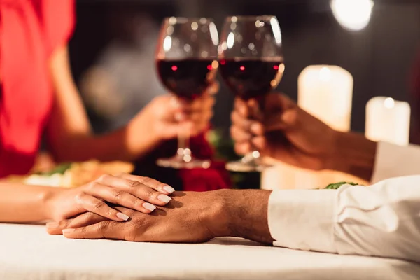 Casal preto irreconhecível segurando as mãos e óculos de claque no restaurante — Fotografia de Stock