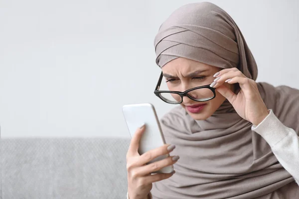 Donna musulmana che ha problemi alla vista, Guardando lo schermo dello smartphone, Occhi strabici — Foto Stock