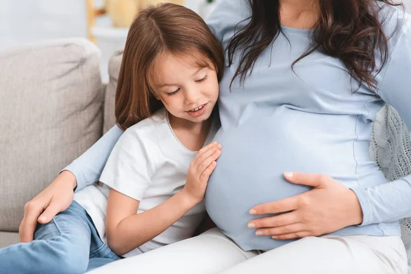 Excited little girl touching her pregnant moms belly — 스톡 사진