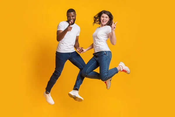 Playful multiracial couple jumping in air, having fun together — Stock Photo, Image