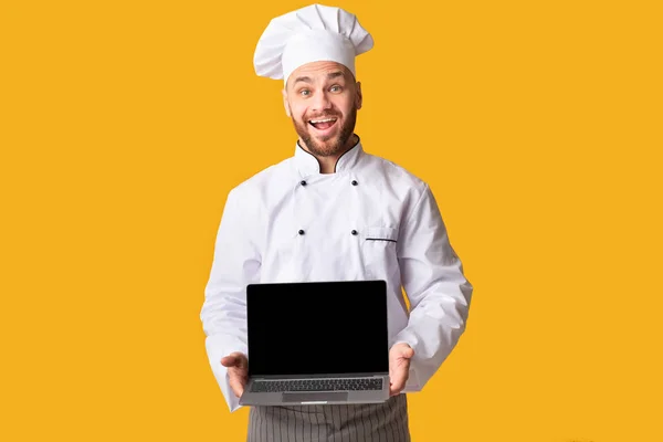 Chef Holding Laptop Computer Pokazuje pusty ekran na żółtym tle — Zdjęcie stockowe