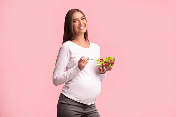 妊娠中の女の子がスタジオで健康的な食べ物を楽しむサラダを食べる — ストック写真