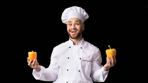 Chef sosteniendo dos pimientos dulces amarillos posando, fondo negro, Panorama —  Fotos de Stock