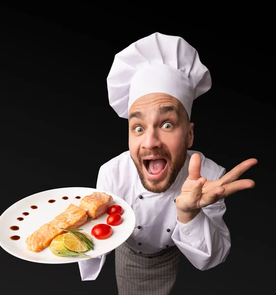Zabawny szef kuchni człowiek pokazano łosoś danie pozowanie w studio, High-Angle — Zdjęcie stockowe
