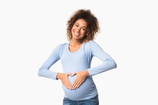 Mujer embarazada afroamericana haciendo señal de corazón en su vientre —  Fotos de Stock