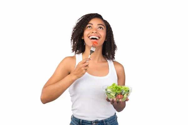 Çatalla salata yiyen mutlu bir afro kadın. — Stok fotoğraf