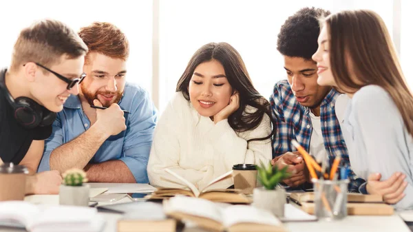 Glückliche Gruppe von Studenten liest Buch in der Bibliothek — Stockfoto