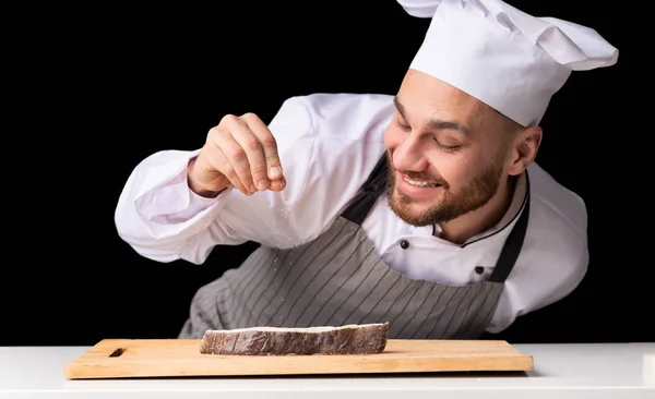 Chef άνθρωπος καρύκευμα σολομό μπριζόλα μαγείρεμα ψάρια σε μαύρο φόντο — Φωτογραφία Αρχείου