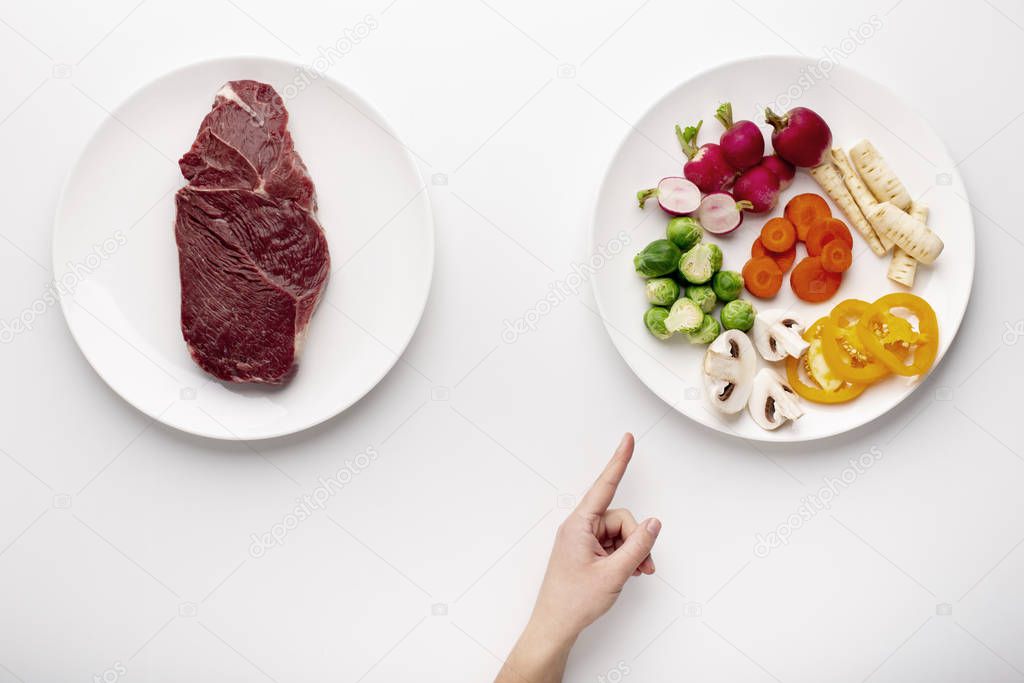 Female hand pointing at plate with organic vegetables