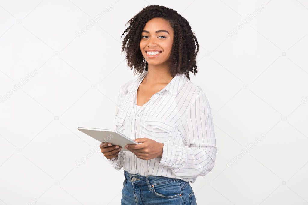 Smiling black girl standing with tablet at studio