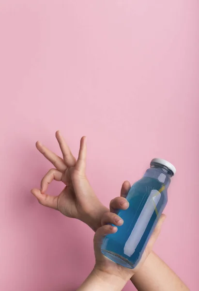 Weibchen halten Flasche mit blauem Isodrink Wasser und zeigen ok Zeichen — Stockfoto