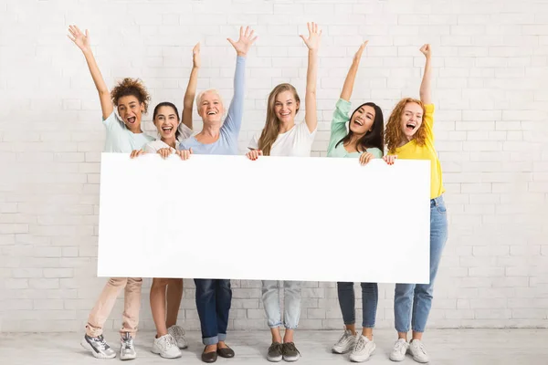Group Of Women Holding Blank Poster Posing Near Wall Indoor — Stock Photo, Image
