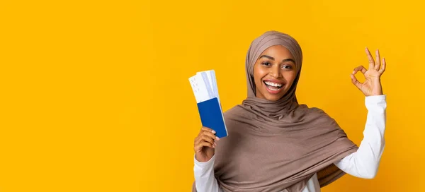Boldog fekete muszlim lány útlevelek és jegyek gesztikuláló oké jel — Stock Fotó