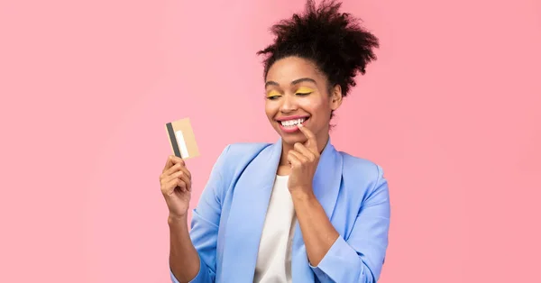 Menina negra segurando cartão de crédito e pensando — Fotografia de Stock