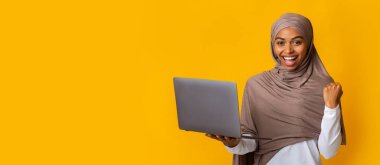 Mutlu Siyah İslami Kız dizüstü bilgisayar tutuyor ve Sevinçle Ünleniyor