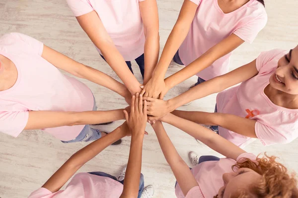 Нерозпізнані жінки У рожевих футболках тримаються за руки по колу, зверху — стокове фото