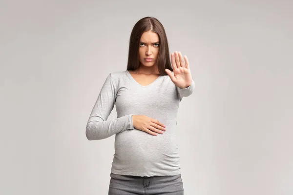Strenge Schwangere gestikuliert und verbietet etwas auf grauem Hintergrund — Stockfoto