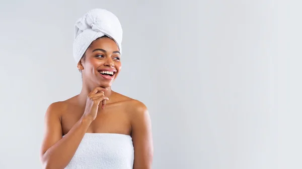 Mulher negra feliz envolto em toalhas olhando para o espaço de cópia — Fotografia de Stock