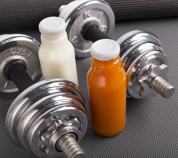 Fresh protein detox cocktails with silver dumbbells on gray — Stock Photo, Image