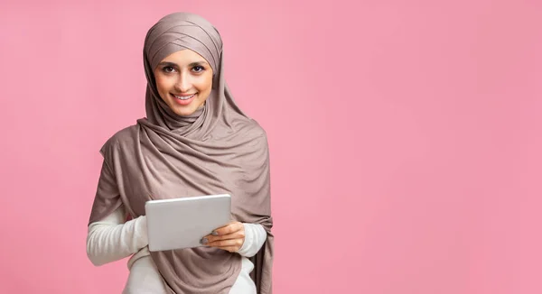 Millennial muslim gadis di hijab dengan tablet digital atas latar belakang merah muda — Stok Foto