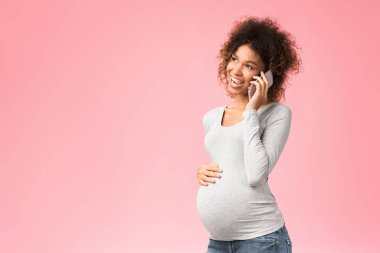 Afro hamile kadın doktoruyla cep telefonuyla konuşuyor.