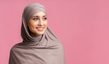tesettürlü çekici müslüman kadın pembe arka plana bakıyor.