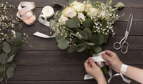 Frau macht Hochzeitsstrauß aus Rosen auf Holz — Stockfoto