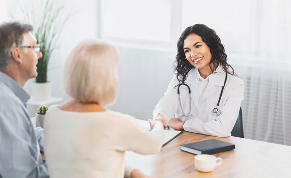 Gelukkig volwassen paar schudden handen met hun verpleegster — Stockfoto