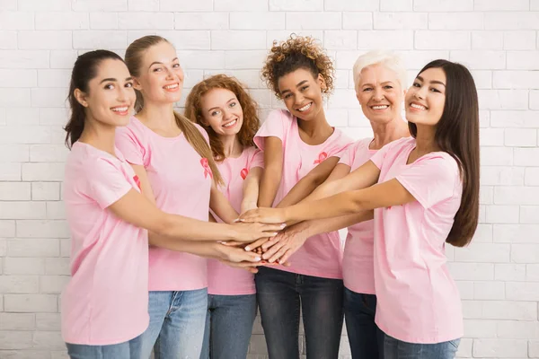 Kobiety w świadomości T-shirty Trzymając się za ręce stojąc przy białym murze — Zdjęcie stockowe