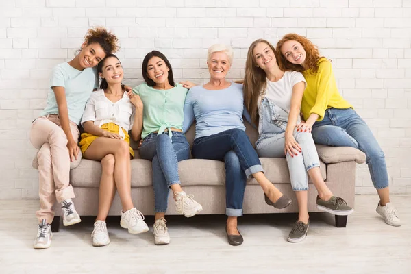 Mulheres de idade diferente sentadas no sofá sorrindo dentro de casa — Fotografia de Stock