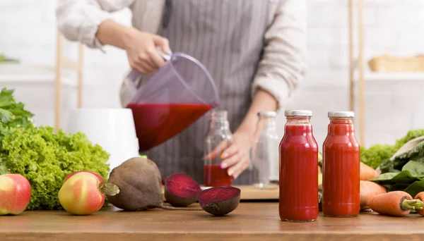 Young woman in apron pouring smoothie from blender into glass bottle — 스톡 사진