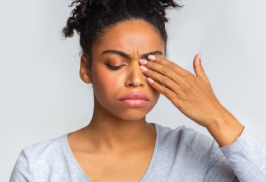 Sad black girl touching her eye, suffering from conjuctivitis clipart