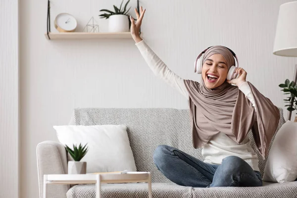 Gadis muslim yang gembira menikmati musik di headphone nirkabel di rumah — Stok Foto