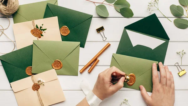 Kvinnliga händer limma upp kuvert med inbjudningar på bröllop — Stockfoto