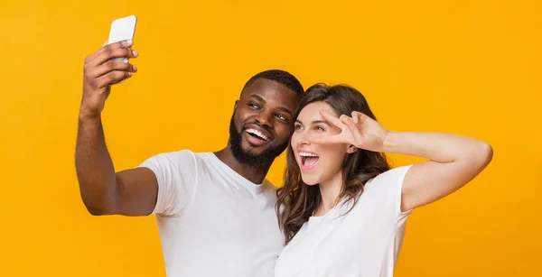 Joyeux couple multiracial capturant selfie sur smartphone, s'amusant ensemble — Photo