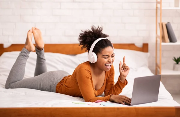 Frau mit Kopfhörer mit Laptop entspannt zu Hause im Bett — Stockfoto