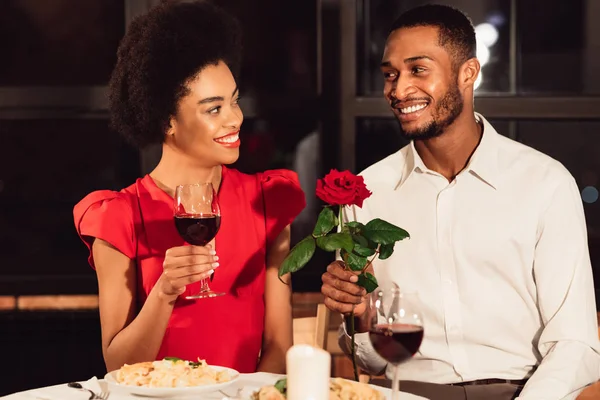 Uomo dando Rose a donna avendo San Valentino data in ristorante — Foto Stock