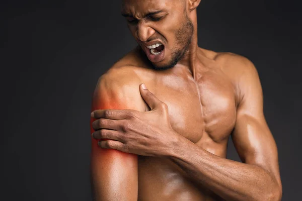 Hombre negro guapo sin camisa que sufre de dolor en el brazo — Foto de Stock