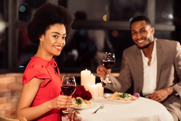 Пара тримає окуляри посміхаючись камеру сидячи у вишуканому ресторані — стокове фото