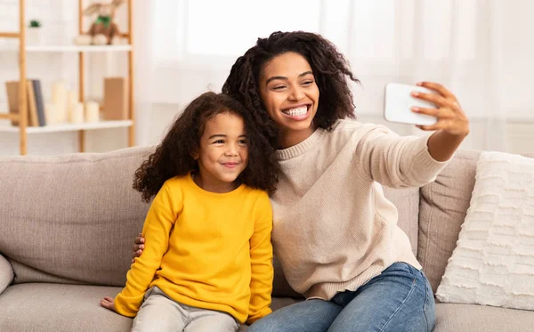 Mère et fille heureuses faisant Selfie assis sur le canapé intérieur — Photo